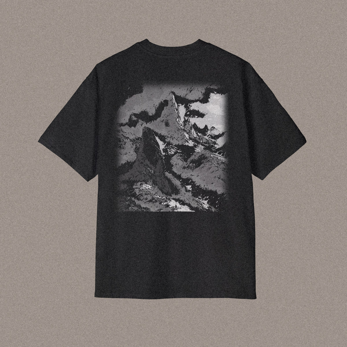 Back of an oversized t-shirt in black, showing the ASCENT design: a dark spire with a paler summit rising behind it, printed in monochrome greys.